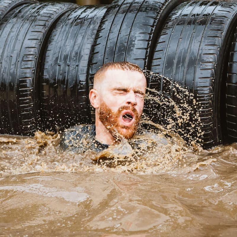 tough mudder charity place - man in muddy water raising money for charity